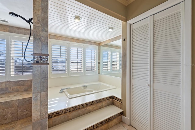 full bath with tile patterned flooring, a garden tub, and a closet