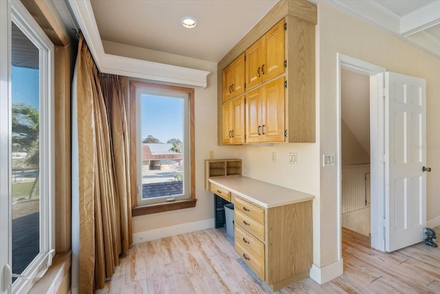 office area featuring baseboards, light wood finished floors, and built in study area