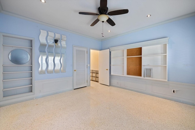 spare room with a ceiling fan, wainscoting, and crown molding