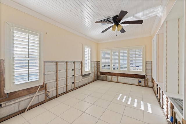 empty room featuring light tile patterned floors, a wainscoted wall, ornamental molding, and ceiling fan