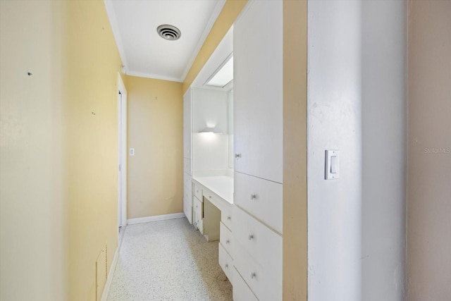 hallway featuring visible vents, baseboards, light speckled floor, and ornamental molding