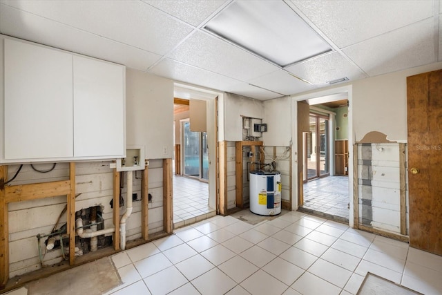 interior space featuring light tile patterned floors, visible vents, a paneled ceiling, and water heater