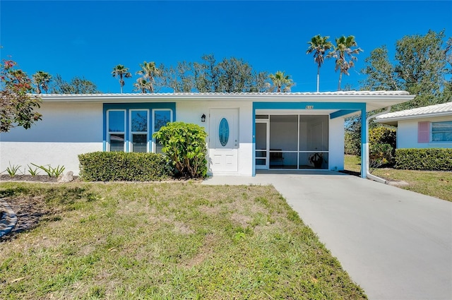 view of front facade featuring a front lawn, a carport, driveway, and stucco siding