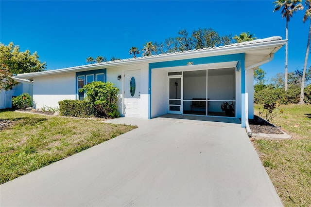 ranch-style home featuring stucco siding, a front yard, and a sunroom