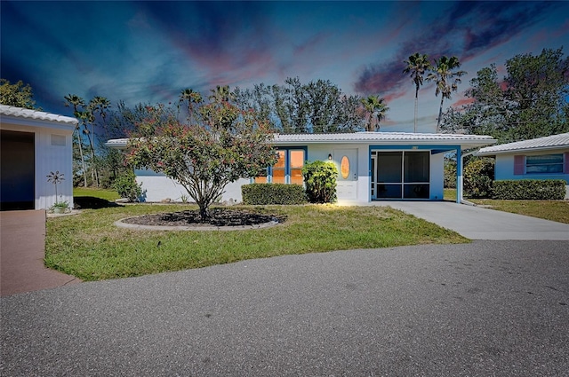 view of front of home with a yard, a carport, and concrete driveway