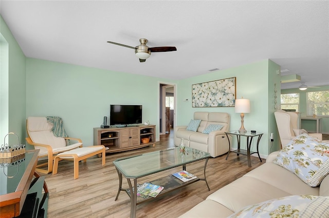 living area with visible vents, baseboards, ceiling fan, and wood finished floors