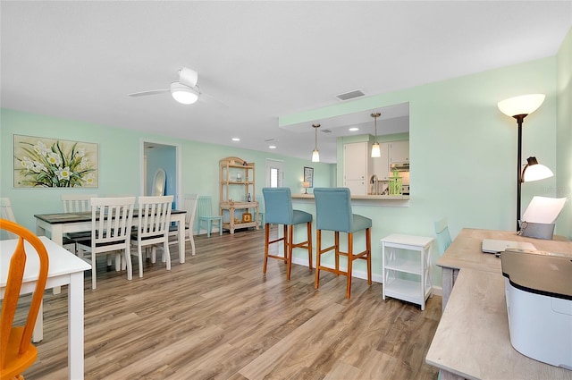 dining room with baseboards, visible vents, light wood finished floors, and ceiling fan