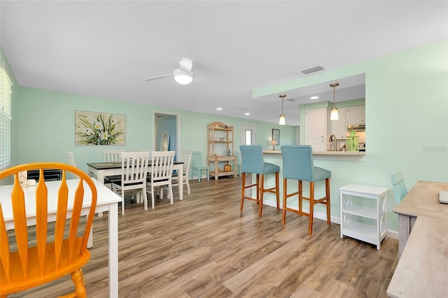 dining room featuring visible vents, light wood-style flooring, baseboards, and a ceiling fan