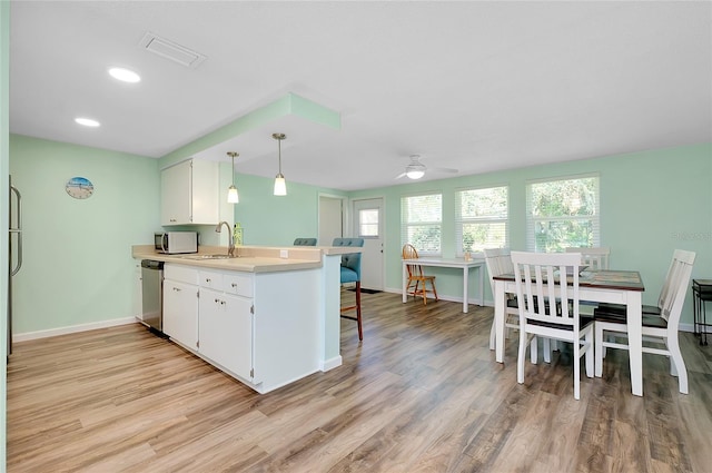 kitchen with visible vents, a sink, stainless steel dishwasher, a peninsula, and white microwave