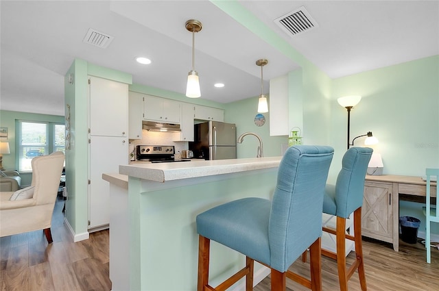 kitchen with under cabinet range hood, visible vents, appliances with stainless steel finishes, and wood finished floors