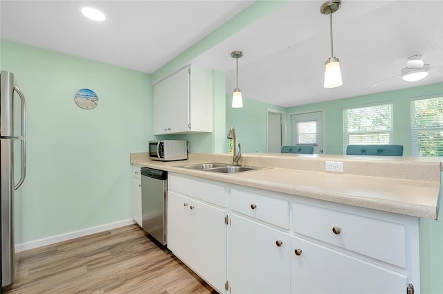 kitchen with white cabinetry, stainless steel appliances, light wood-type flooring, and a sink