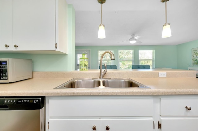 kitchen with white microwave, dishwasher, light countertops, white cabinetry, and a sink