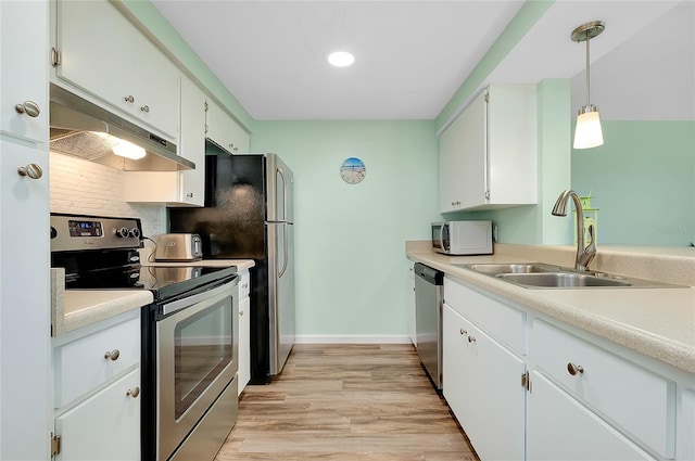 kitchen featuring under cabinet range hood, white cabinets, appliances with stainless steel finishes, and a sink