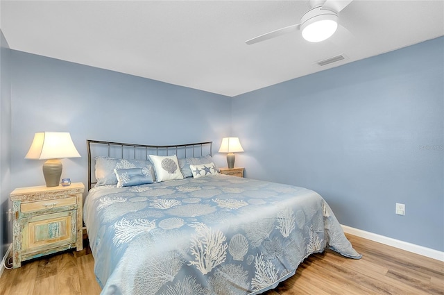 bedroom with ceiling fan, wood finished floors, visible vents, and baseboards