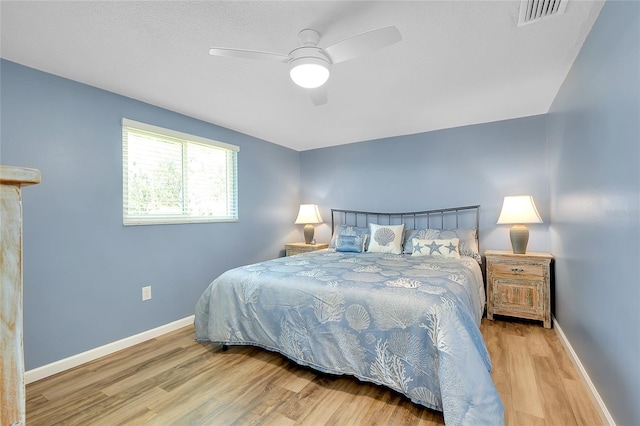 bedroom featuring a ceiling fan, wood finished floors, visible vents, and baseboards