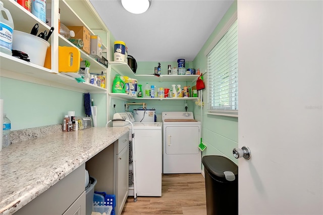 clothes washing area with cabinet space, washing machine and dryer, and light wood-style floors