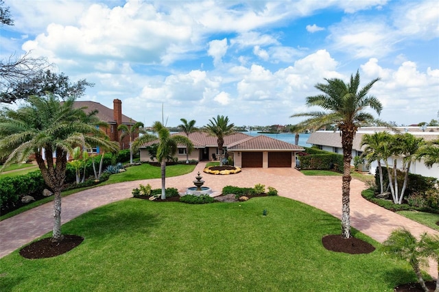 view of front of property featuring a tiled roof, a front lawn, curved driveway, and an attached garage