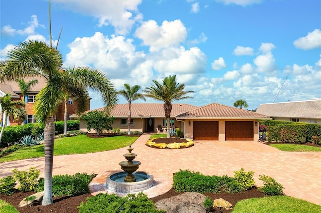 view of front facade with a tiled roof, an attached garage, decorative driveway, a front lawn, and stucco siding