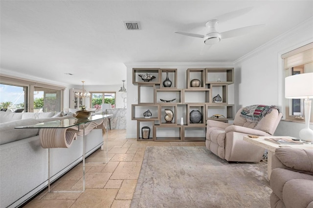 living area featuring visible vents, ornamental molding, ceiling fan with notable chandelier, and stone tile flooring