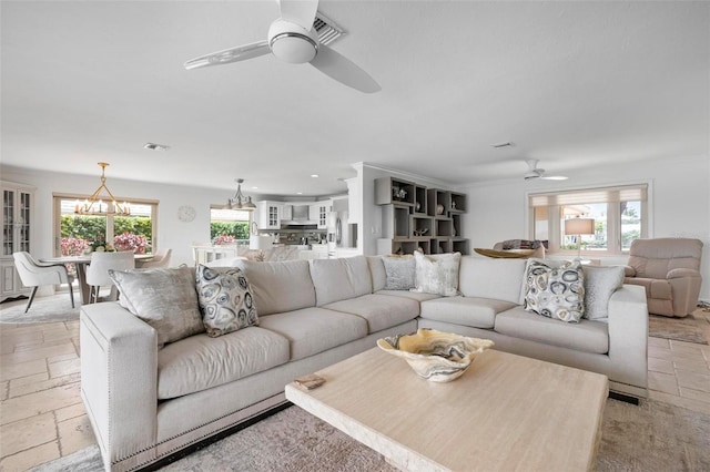 living room featuring a wealth of natural light, visible vents, and stone tile flooring