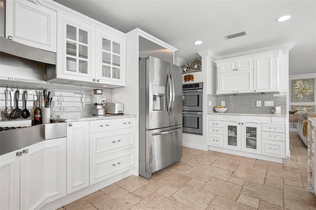 kitchen featuring white cabinets, visible vents, stainless steel appliances, and stone tile flooring