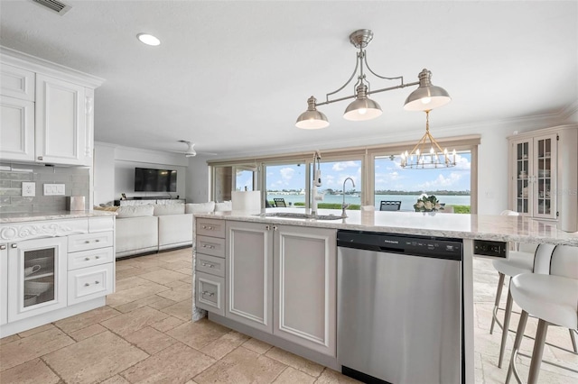 kitchen featuring ornamental molding, open floor plan, stone tile flooring, stainless steel dishwasher, and a sink