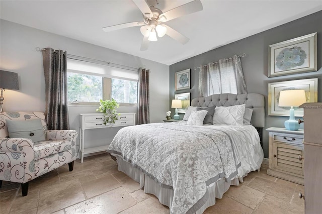 bedroom featuring a ceiling fan and stone tile floors