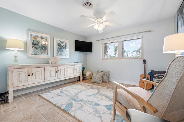 living area featuring a ceiling fan, baseboards, visible vents, and stone tile flooring