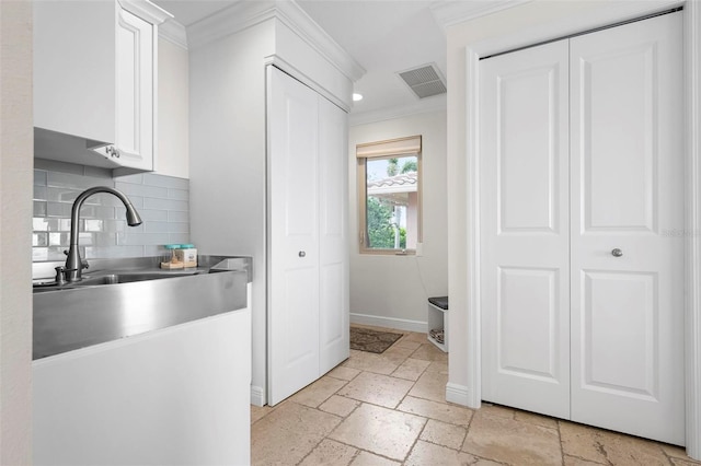 kitchen featuring stone tile floors, visible vents, ornamental molding, white cabinets, and baseboards