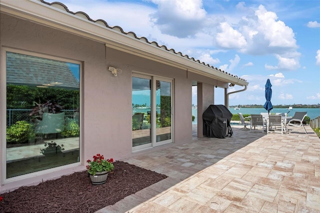 view of patio featuring a water view, outdoor dining area, and area for grilling