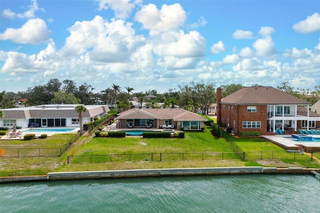 rear view of house with a patio area, a lawn, a water view, and a fenced backyard