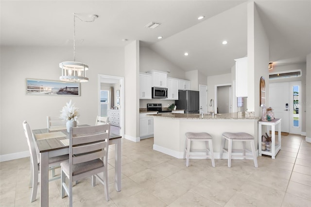 kitchen featuring stainless steel appliances, visible vents, white cabinets, a sink, and a kitchen breakfast bar