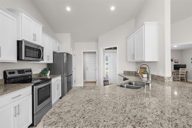 kitchen with light stone counters, recessed lighting, a sink, white cabinets, and appliances with stainless steel finishes