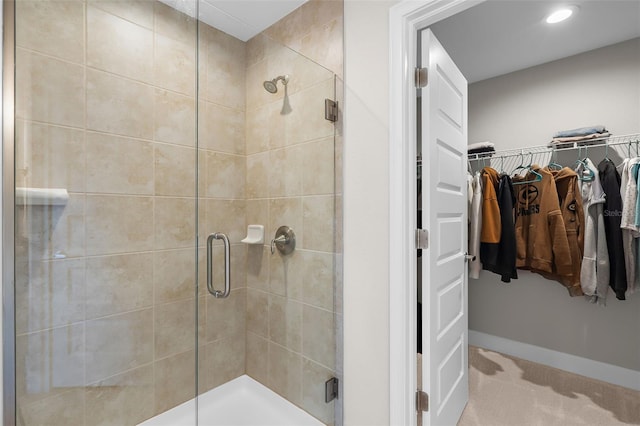 full bath featuring a spacious closet, a shower stall, and baseboards