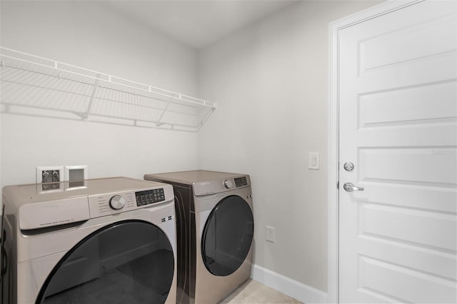 clothes washing area with laundry area, washing machine and dryer, and baseboards