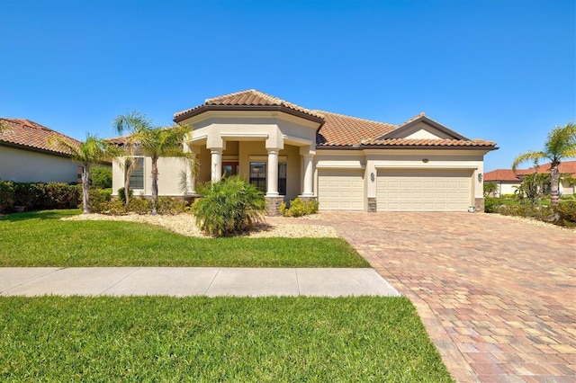 mediterranean / spanish-style home featuring an attached garage, a tiled roof, decorative driveway, stucco siding, and a front lawn