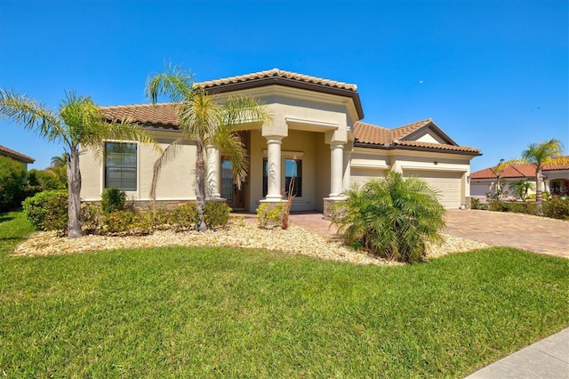 mediterranean / spanish house with a front lawn, a tiled roof, and an attached garage