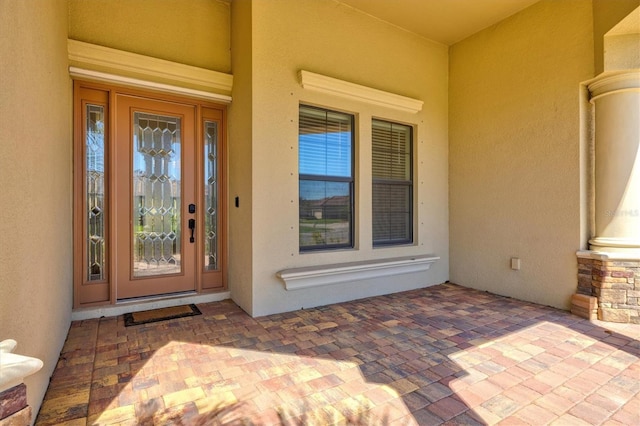 doorway to property featuring stone siding and stucco siding