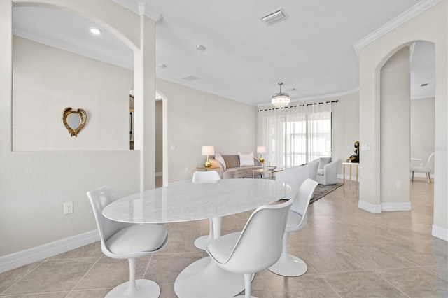 dining area with baseboards, visible vents, arched walkways, tile patterned floors, and crown molding