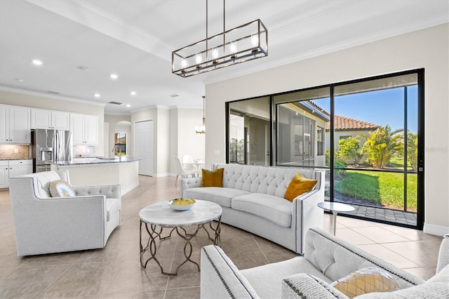 living room with ornamental molding, a notable chandelier, baseboards, and light tile patterned floors