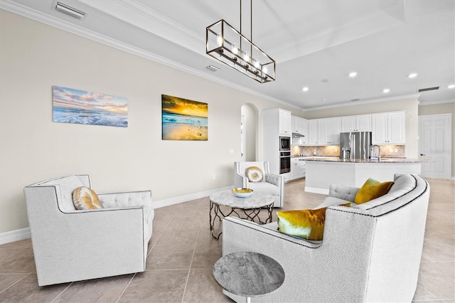 living room featuring arched walkways, light tile patterned flooring, visible vents, baseboards, and ornamental molding