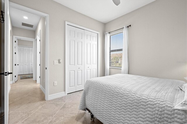 bedroom with a closet, visible vents, a ceiling fan, light tile patterned flooring, and baseboards