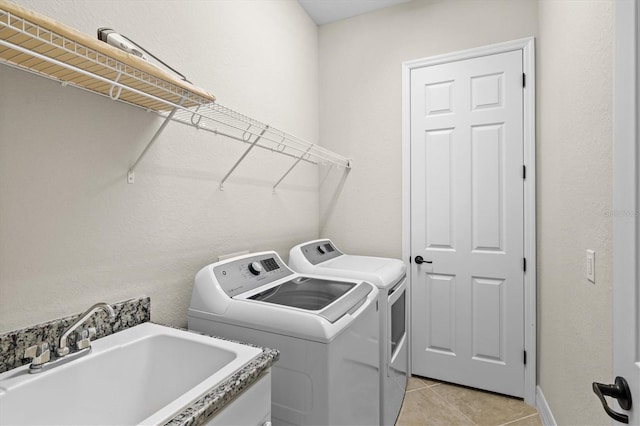 laundry room with laundry area, light tile patterned floors, a sink, and independent washer and dryer