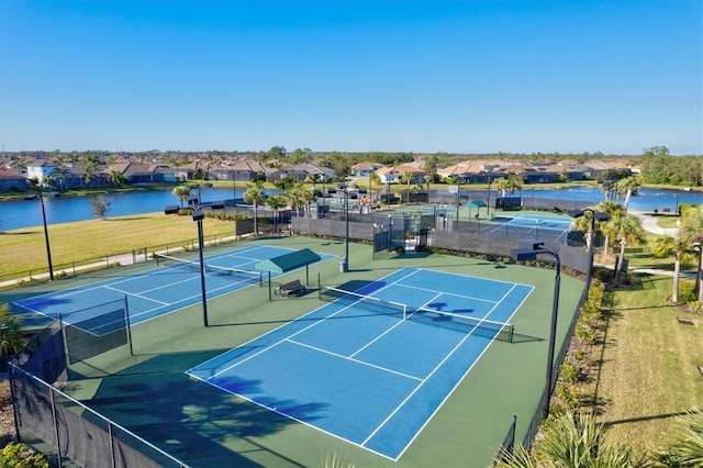 view of sport court with a water view, fence, and a residential view