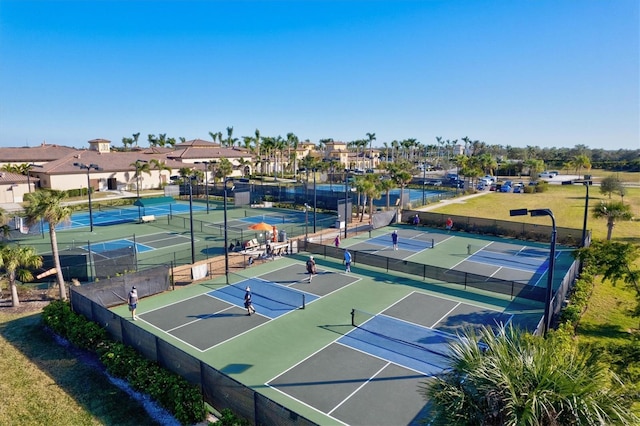 view of sport court featuring a lawn, fence, and a residential view