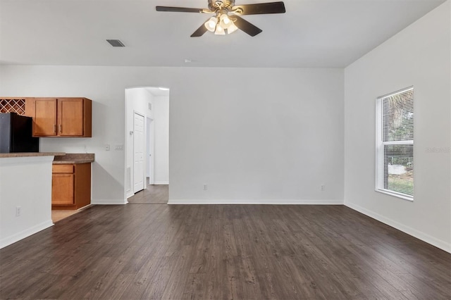 unfurnished living room featuring visible vents, dark wood-style floors, arched walkways, baseboards, and ceiling fan