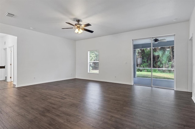 unfurnished room featuring visible vents, dark wood-type flooring, baseboards, ceiling fan, and arched walkways