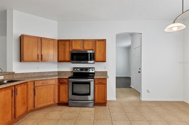 kitchen with a sink, stainless steel appliances, and brown cabinetry