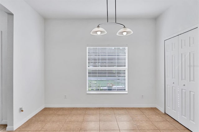 unfurnished dining area featuring light tile patterned floors and baseboards