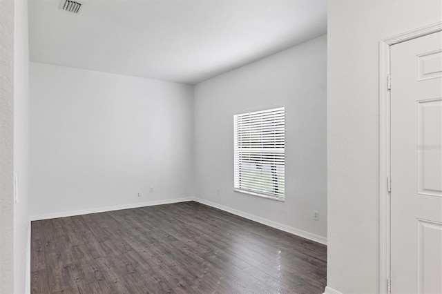 unfurnished room featuring dark wood-style floors, visible vents, and baseboards